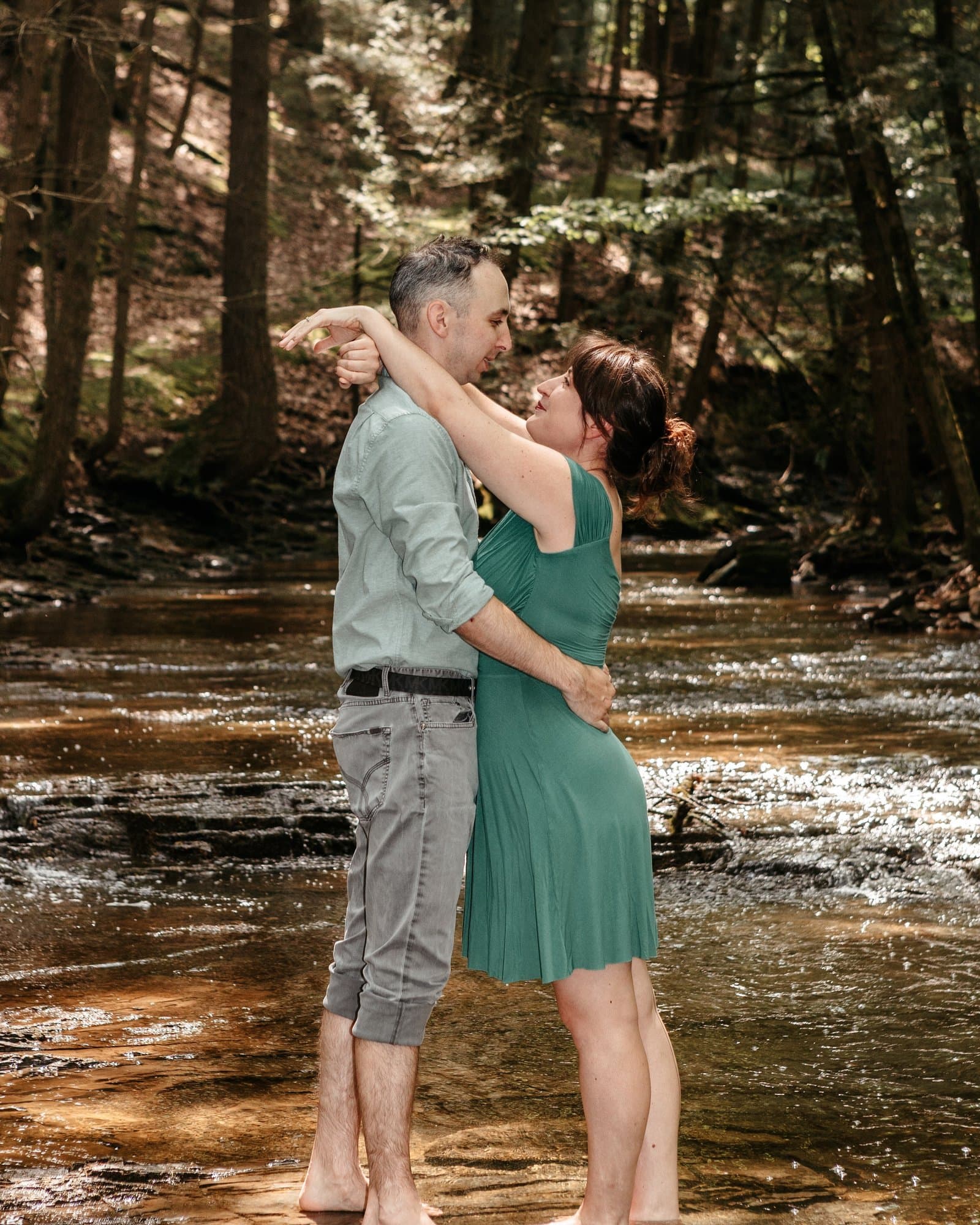 Couple embracing barefoot in a forest creek during their engagement session