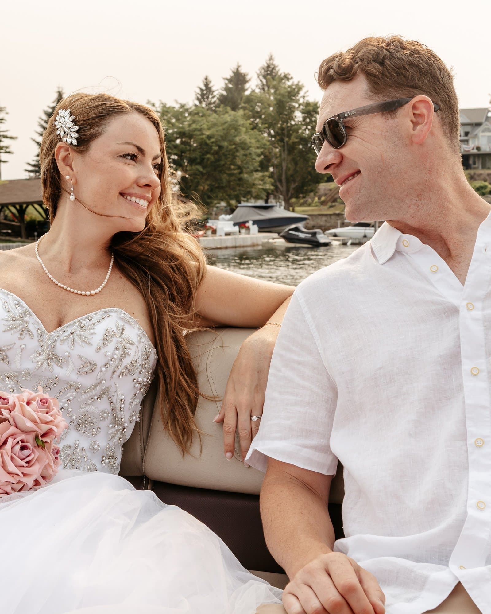 Bride and groom smiling at each other on a boat on the lake