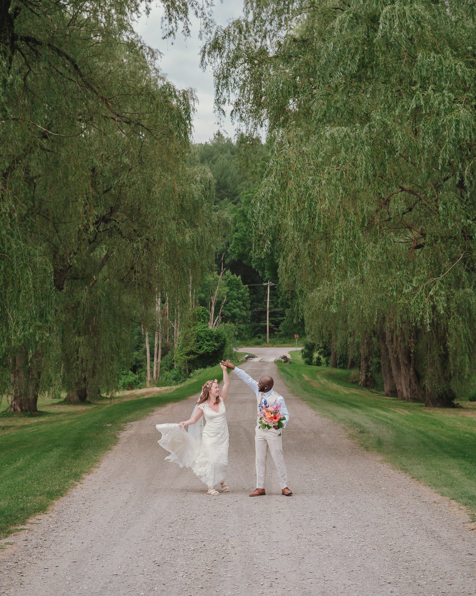 Groom twirling the bride on a willow-lined country lane