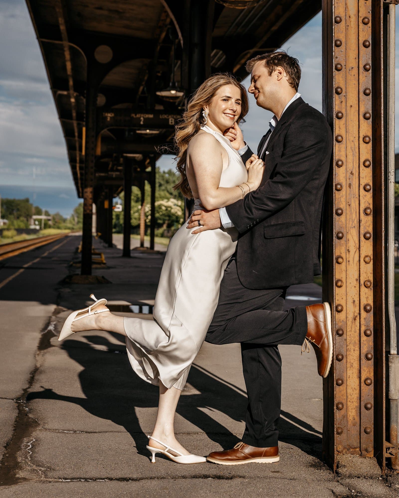Elegant couple embracing under the canopy of a historic train station platform