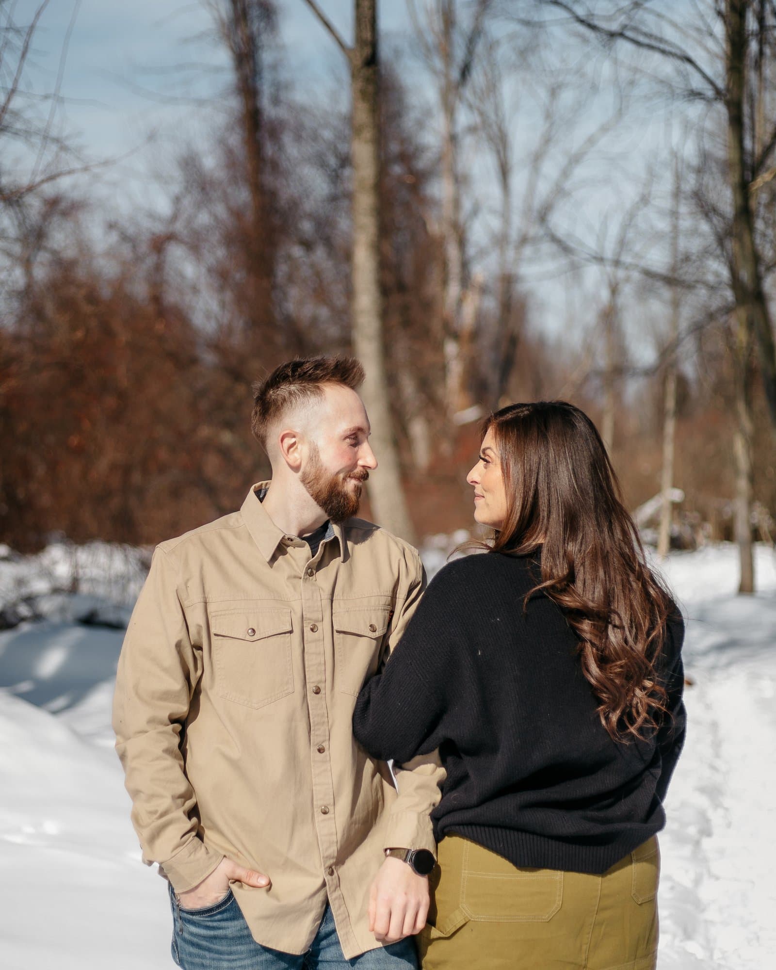 Couple walking arm in arm on a snow-covered trail in winter woods