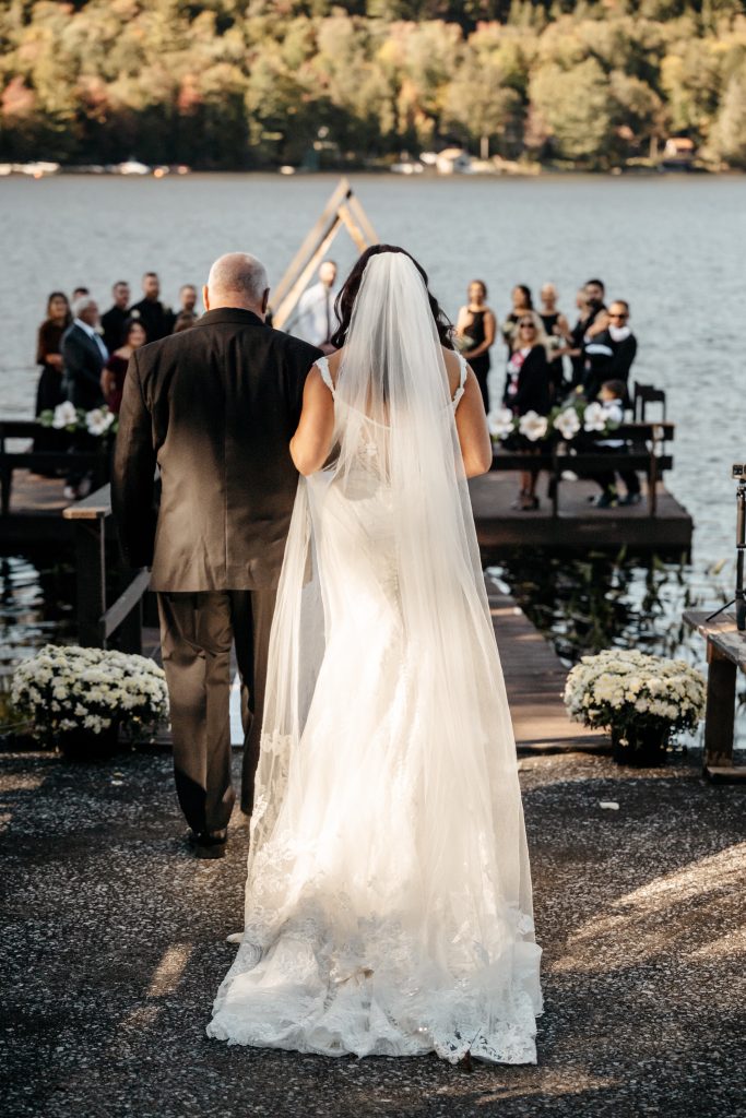 A bride walks down the aisle with her father after learning the average wedding cost in upstate ny
