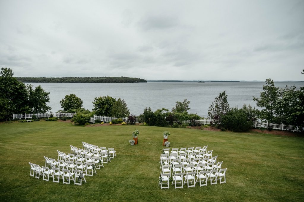 An outdoor wedding is set up facing a beautiful lake in one of the Upstate New York wedding venues