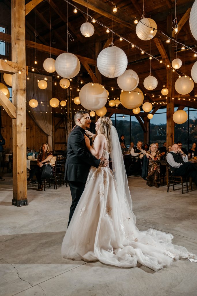A bride and groom share a first dance under paper lanterns at their 
Upstate New York wedding venue