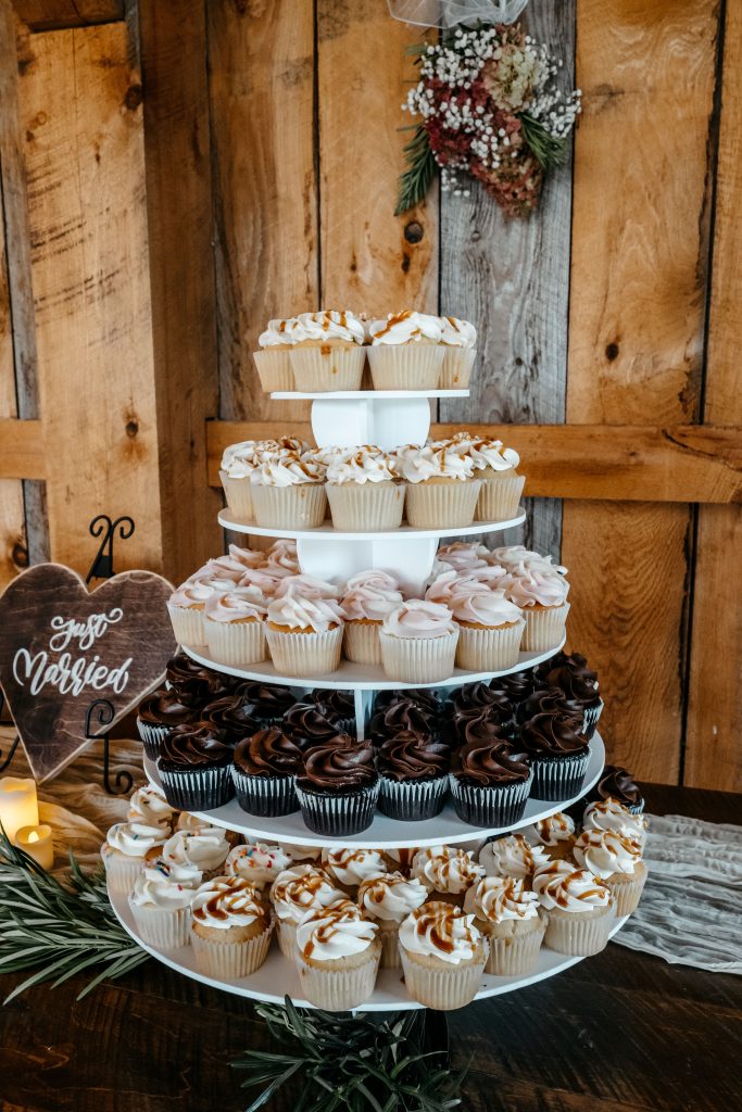 A cupcake display sits on a wooden table at a wedding venue in Gables and Gardens granville ny