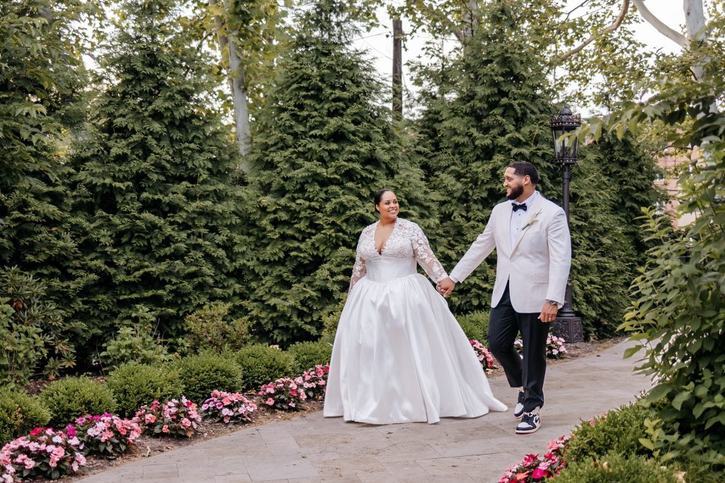 A bride and groom walk down a garden path while getting married in upstate new york